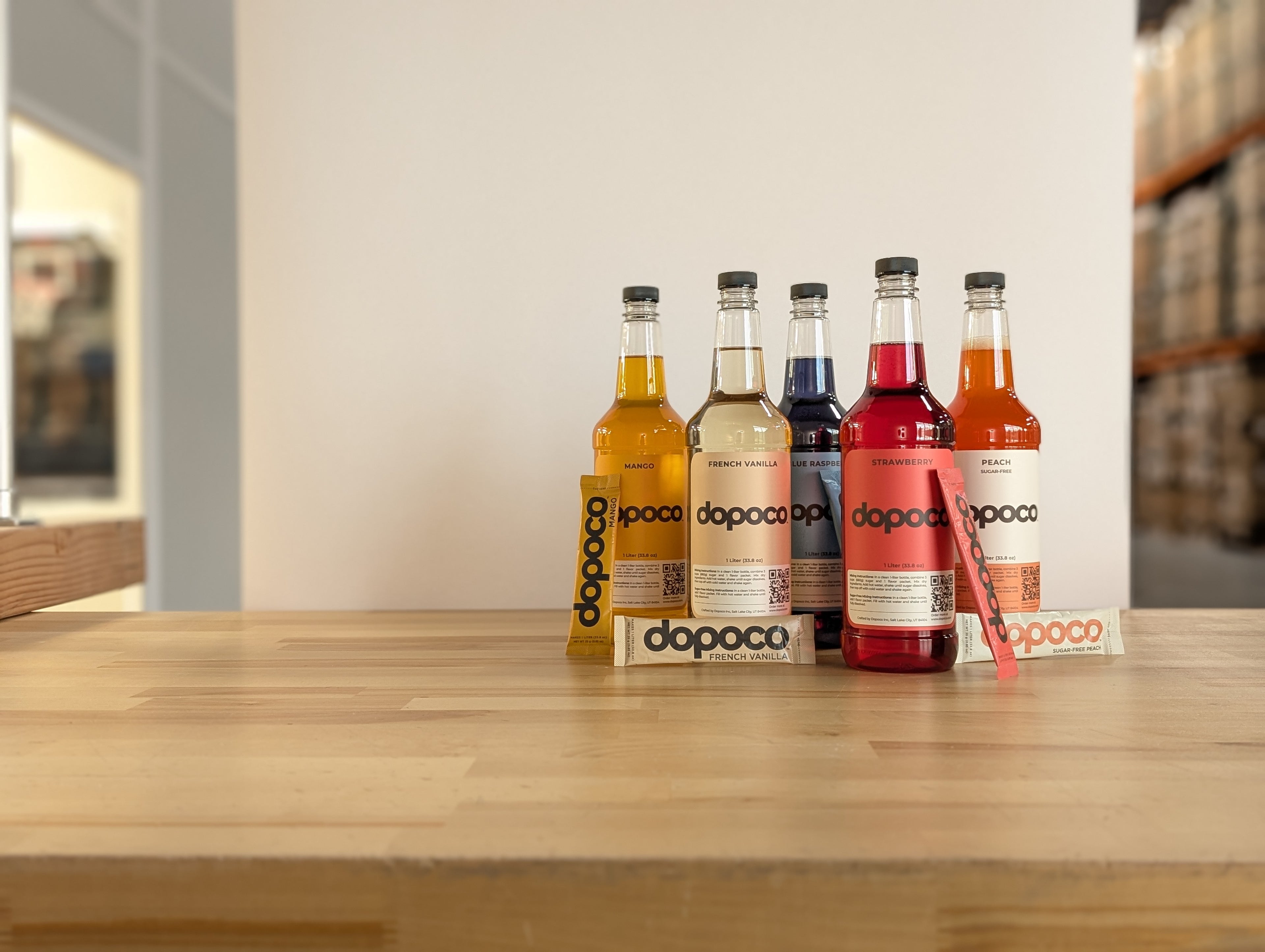 Five bottles of dopoco syrups on a wooden surface with a blurred background