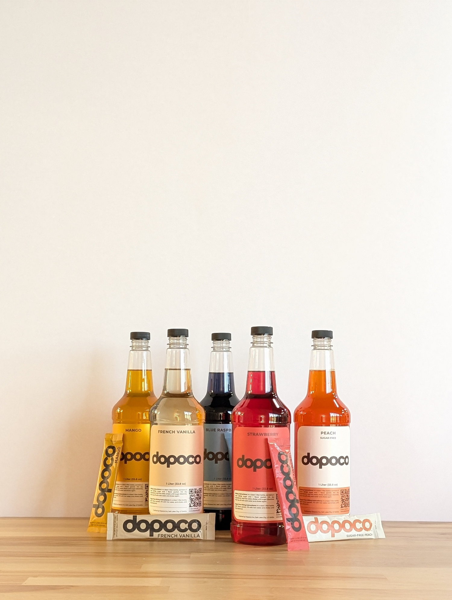 Bottles of Dopoco drinks on a wooden surface with a white background