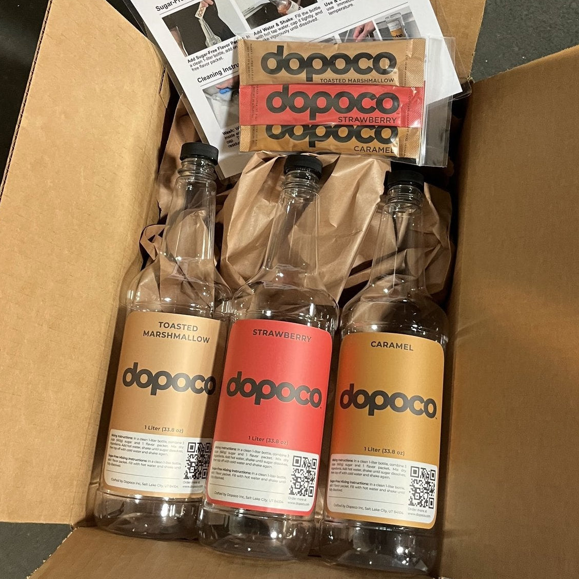 Box containing Dopoco bottles and promotional materials on a dark surface